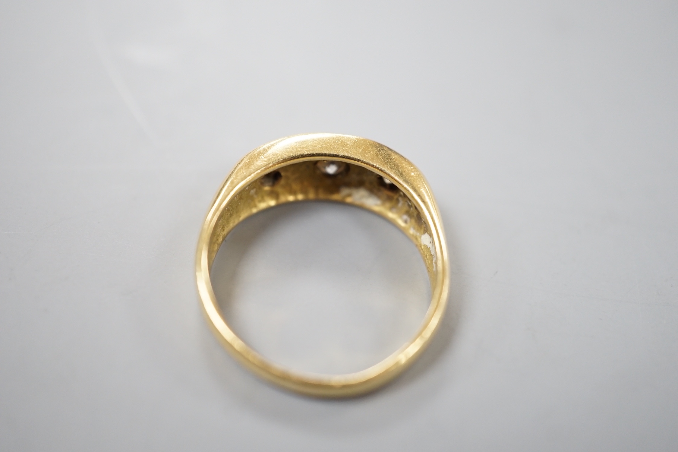 An 18ct gold and three stone gypsy set diamond ring, size S, gross weight 7.1 grams.